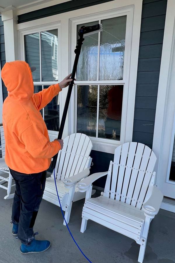 Crew member cleaning porch windows with a water-fed pole